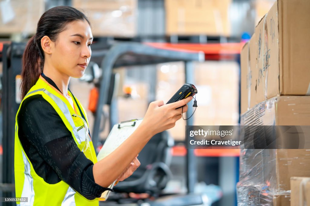 The warehouse worker with scanner making review of goods compare data with clipboard in warehouse.
