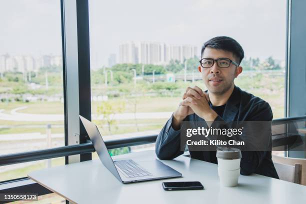 asian businessman sitting looking at camera with hands clasped - master of business administration stock pictures, royalty-free photos & images