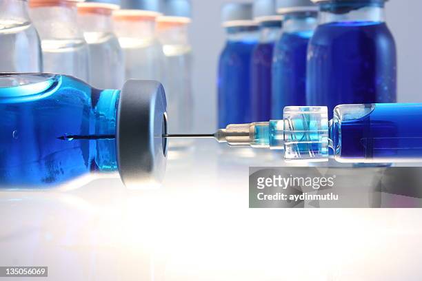 syringe with blue liquid entering bottle with more behind - alternative therapy stock pictures, royalty-free photos & images