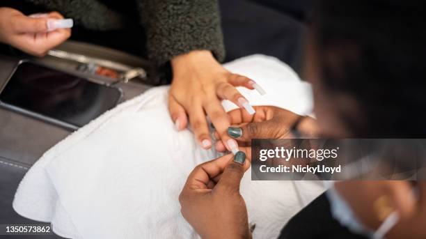 nail extension process in beauty salon - fake hand stock pictures, royalty-free photos & images