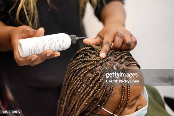 hairdresser putting oil on braided hair of her client in salon - human scalp stock pictures, royalty-free photos & images