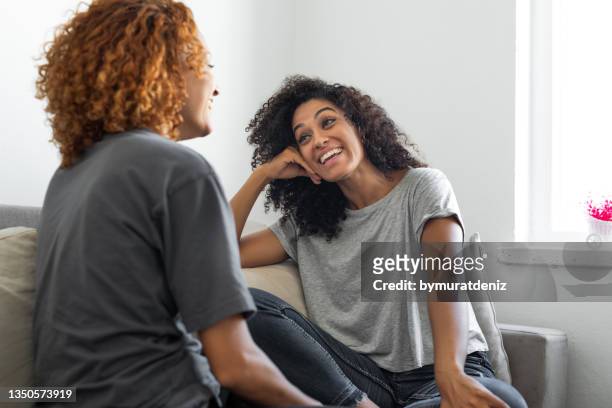 two women talking and relaxing on the sofa at home - two women talking stockfoto's en -beelden