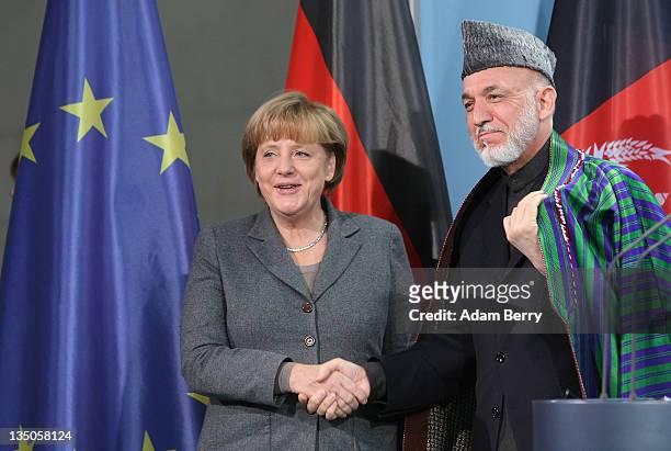 Afghan president Hamid Karzai shakes hands with German Chancellor Angela Merkel after a news conference in the German federal chancellery on December...