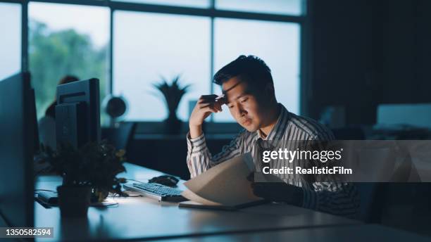 アジアのビジネスマンは夜遅くまで働く - asian man sitting at desk ストックフォトと画像