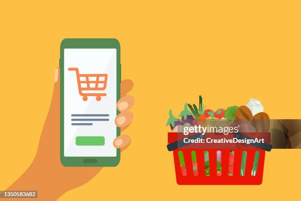 illustrazioni stock, clip art, cartoni animati e icone di tendenza di shopping di generi alimentari online e concetto di consegna con carrello della spesa pieno di verdure e mano umana che tiene il telefono cellulare. - ordine