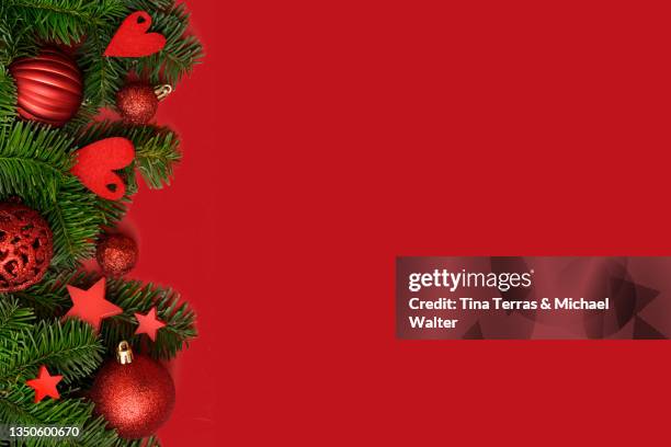 fir branches and red christmas tree decorations against red background. top view. flatlay. - christmas tree close up stock pictures, royalty-free photos & images