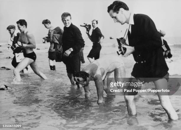 Photographers and members of the media surround Danish swimmer Greta Andersen as she emerges from the waters of the English Channel after her Channel...