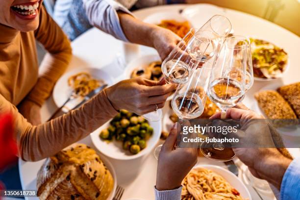 scatto di persone che brindano con champagne durante un pasto - cena capodanno foto e immagini stock