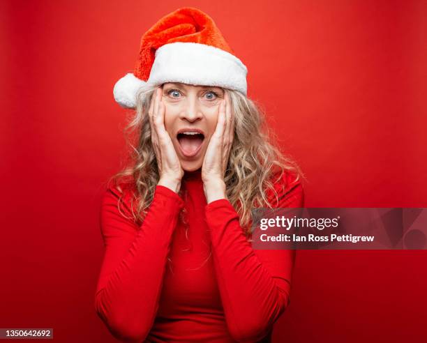 beautiful middle-aged woman wearing santa hat - santa portrait stock pictures, royalty-free photos & images