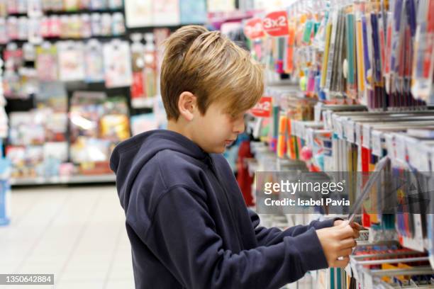 boy shopping for school supplies in a supermarket - material escolar fotografías e imágenes de stock