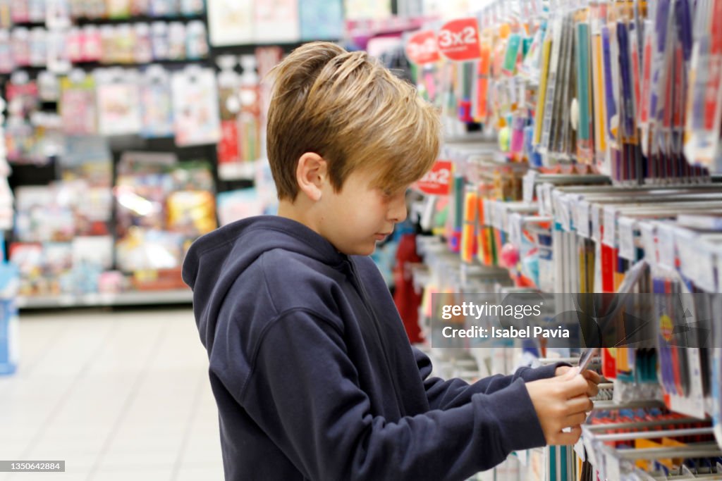 Boy shopping for school supplies in a supermarket