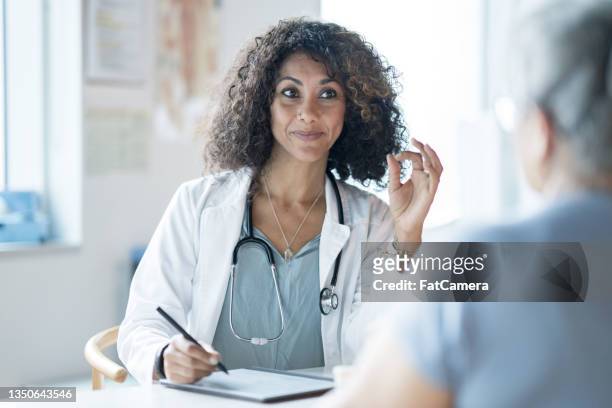 arzt im gespräch mit einem patienten - caucasian doctor and nurse using tablet computer stock-fotos und bilder