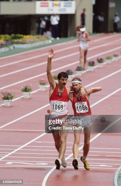 Gold medalist Aleksandr Potashov of the Soviet Union raises his arm in celebration as he crosses the finishing line with compatriot and silver...