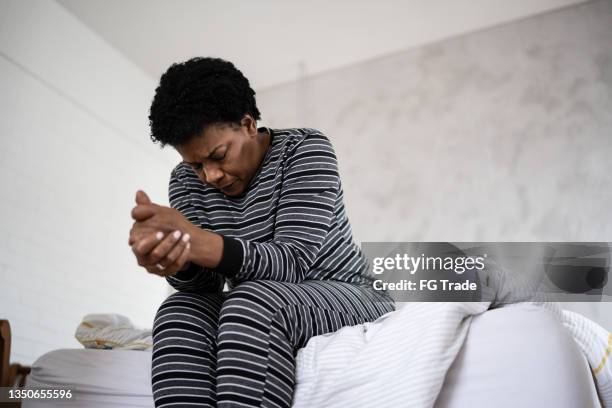 reife frau, die sich im bett zu hause schlecht fühlt - man worried sitting stock-fotos und bilder