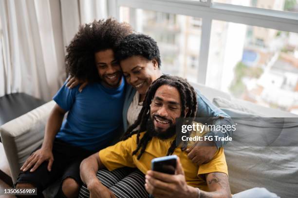 mother and sons doing a video call on smartphone at home - 50 watching video stock pictures, royalty-free photos & images