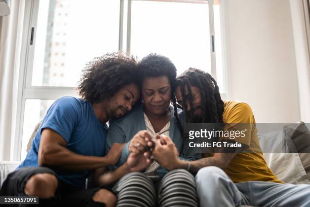 sons consoling mother at home - sibling support stock pictures, royalty-free photos & images