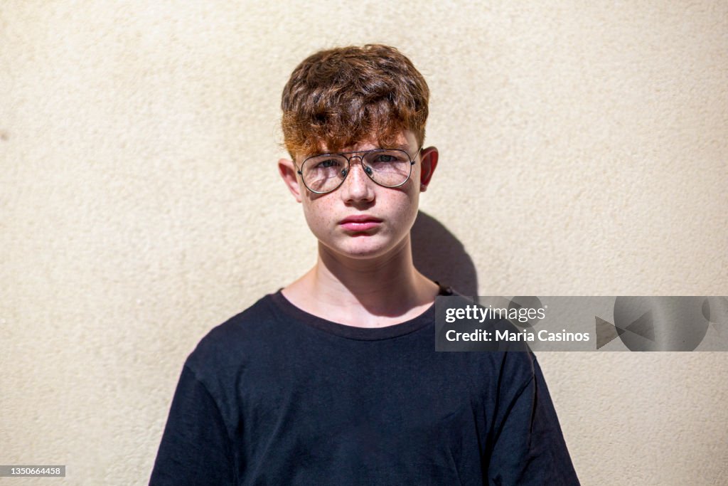 Portrait of red-haired teen boy with freckles and eyeglasses