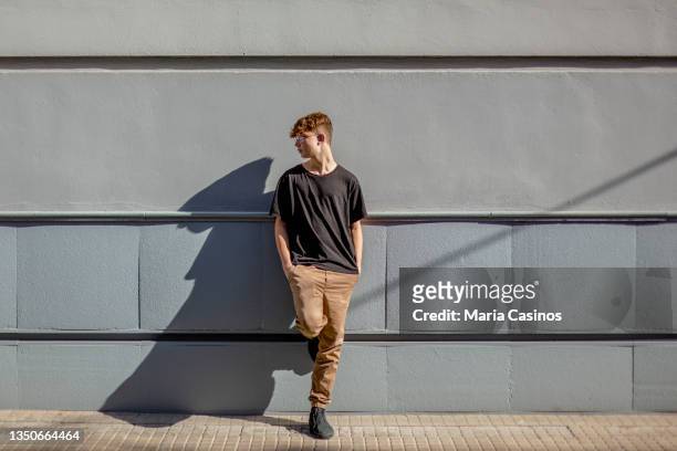 red-haired teen boy with freckles, leaning against a wall - 15 year old model stock pictures, royalty-free photos & images