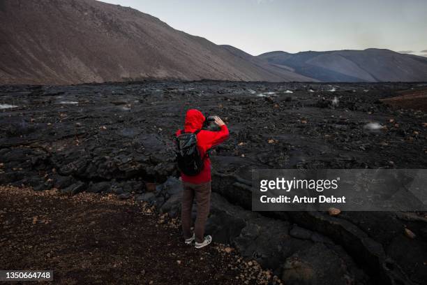 guy photographing the black lava of the fagradalsfjall volcano in iceland. - volcanic landscape stock pictures, royalty-free photos & images