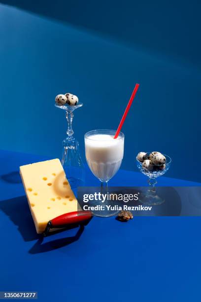 glass of milk, cheese, quail eggs, nuts on the blue background - still life not people imagens e fotografias de stock