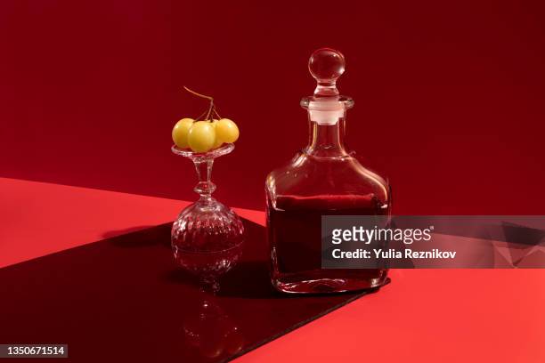 a red wine carafe on the red background - still life fotografías e imágenes de stock