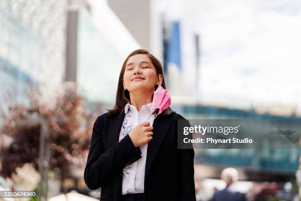 woman during pandemic isolation at city. removing mask from face - removing surgical mask stock pictures, royalty-free photos & images