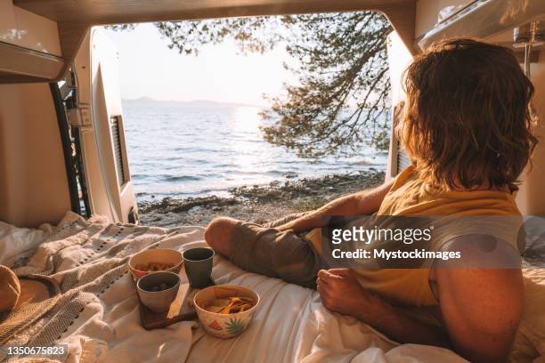 man lying in a van looking at ocean - aperitif stockfoto's en -beelden