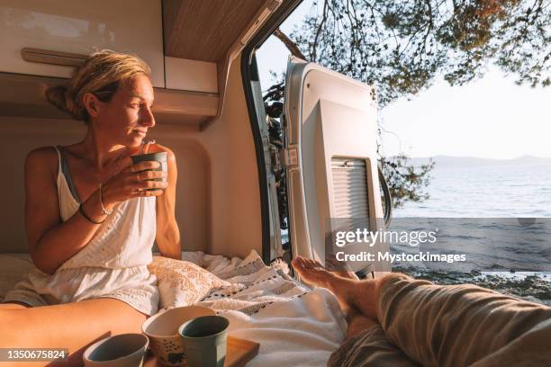 paar in einem van bei sonnenuntergang trinken - camper van stock-fotos und bilder