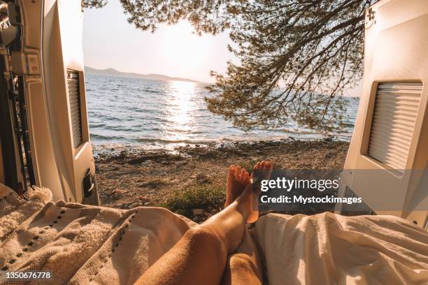 woman lying in a van looking at the ocean, pov - rv beach stock pictures, royalty-free photos & images