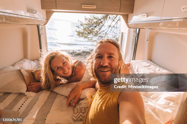 couple lying at the back of a van take selfie - vanlife stock pictures, royalty-free photos & images