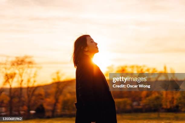 beautiful young woman feeling hopeful and embracing nature. - winter sunset stock pictures, royalty-free photos & images