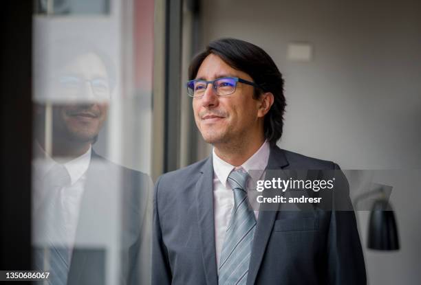 business man wearing glasses while looking through the window of his office - male portrait suit and tie 40 year old stock pictures, royalty-free photos & images