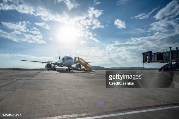 jet airplane at the airport field with docked ladder - tarmac stockfoto's en -beelden