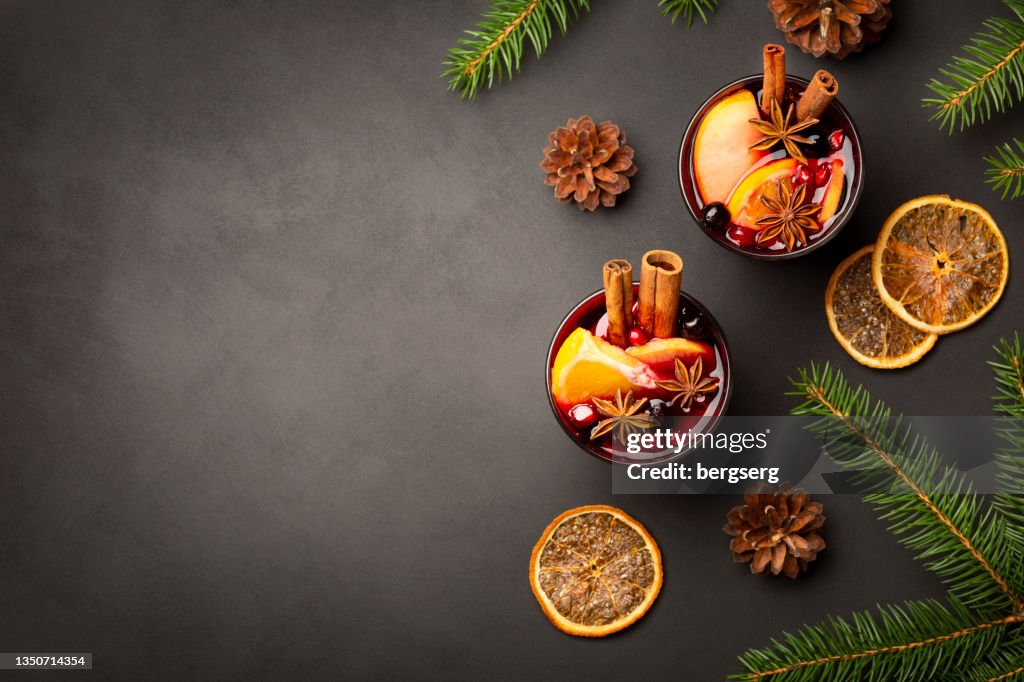 Christmas Background with Two Glasses of Mulled Red Wine, Fir Tree, Cinnamon, Orange, Spices and Copy Space. Flat Lay