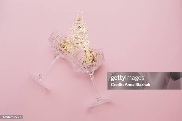 champagne glasses filled with golden confetti on pink background - champagne glass stock-fotos und bilder