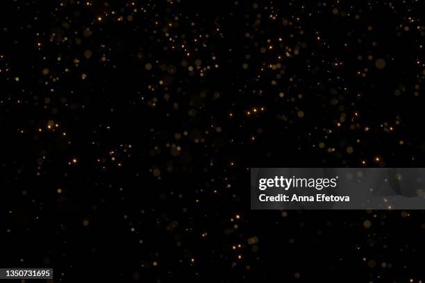 many festive blurred golden confetti on black background. concept of new year or birthday celebration. perfect backdrop for your design - gold glitter stock-fotos und bilder