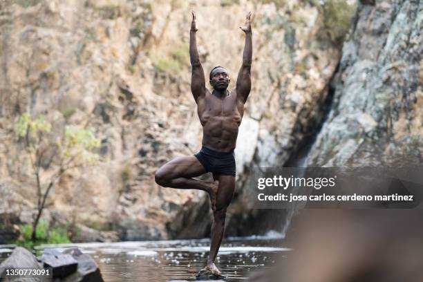 african man yoga teacher, practicing in a river - pilates abstract stock pictures, royalty-free photos & images