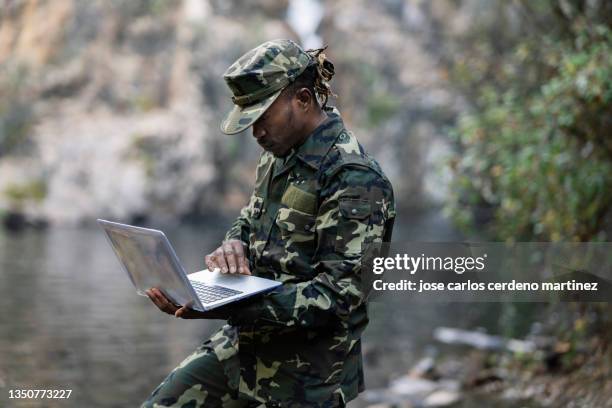 african military man, with laptop, on duty in the jungle - military communications stock pictures, royalty-free photos & images