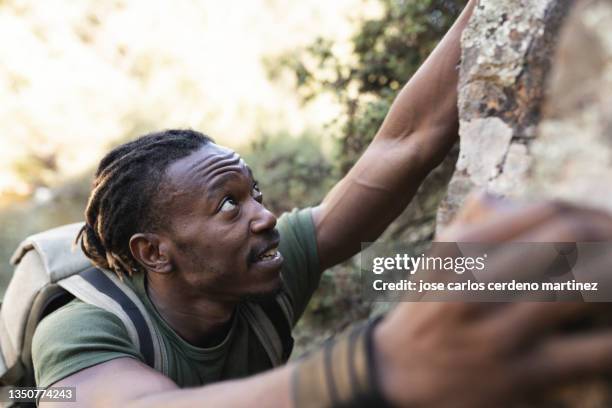 man in camouflage clothing climbing a mountain - leather training shoes stock-fotos und bilder