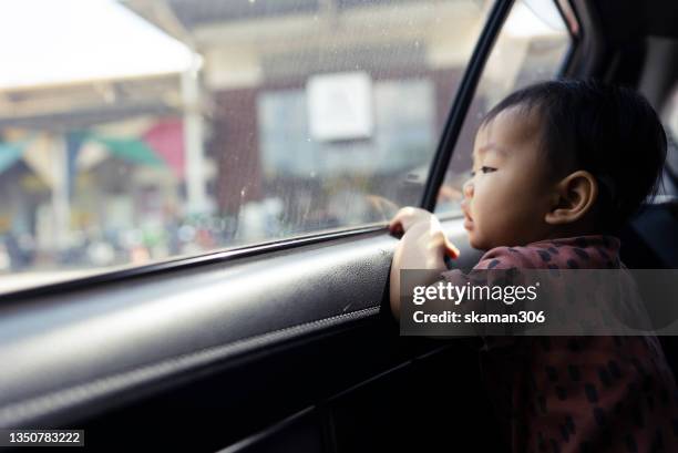 asian baby looking forward outside the car window and waiting for parent - kidnapping girls stock pictures, royalty-free photos & images