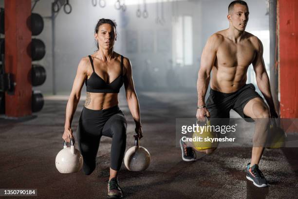 jovem casal atlético se exercitando com sinos de chaleira em uma academia. - culturismo - fotografias e filmes do acervo