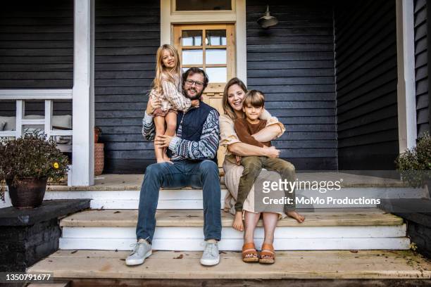 portrait of young family in front of farmhouse - two parents stock-fotos und bilder