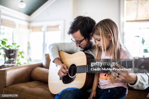 father teaching daughter how to play guitar - child wearing adult glasses stock pictures, royalty-free photos & images