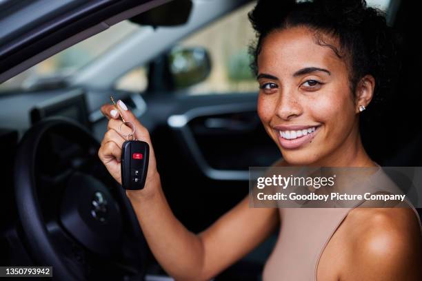 smiling young woman holding keys while sitting in her car - chave de carro imagens e fotografias de stock