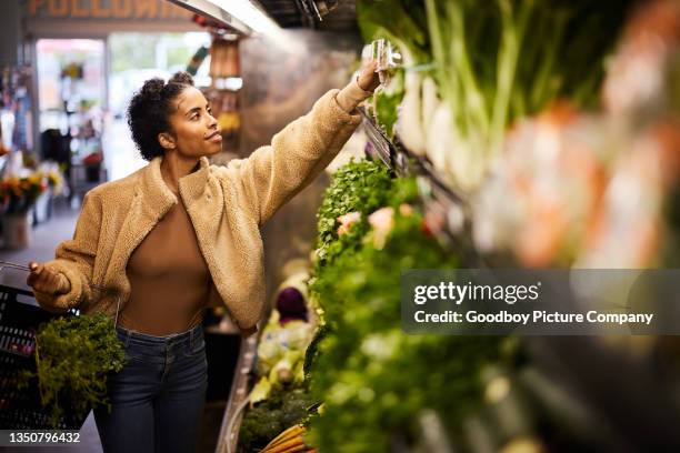 young woman browsing the fresh vegetable aisle in a greengrocer's - produce aisle stock pictures, royalty-free photos & images