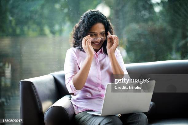 businesswoman video chatting using laptop on sofa at office - reading glasses 個照片及圖片檔