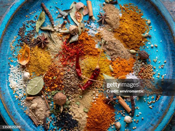 variety of colorful, organic, dried, vibrant indian food spices on an old turquoise-colored ceramic plate. - cominho imagens e fotografias de stock