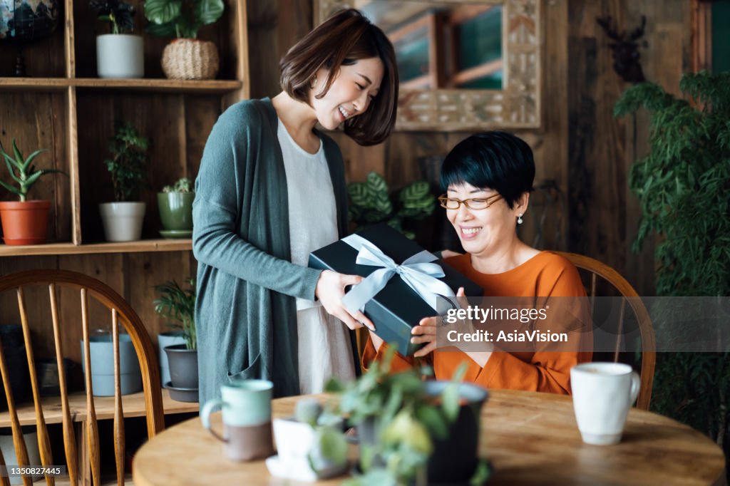 Una madre asiática mayor recibiendo un regalo de su hija en casa. El amor entre madre e hija. La alegría de dar y recibir