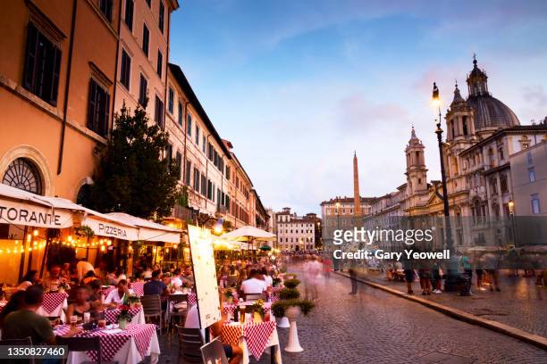 people dining outside in piazza navona in rome at dusk - rome italië stockfoto's en -beelden