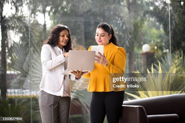 zwei geschäftsfrauen, die laptop und digitales tablet im büro verwenden - fun experience stock-fotos und bilder